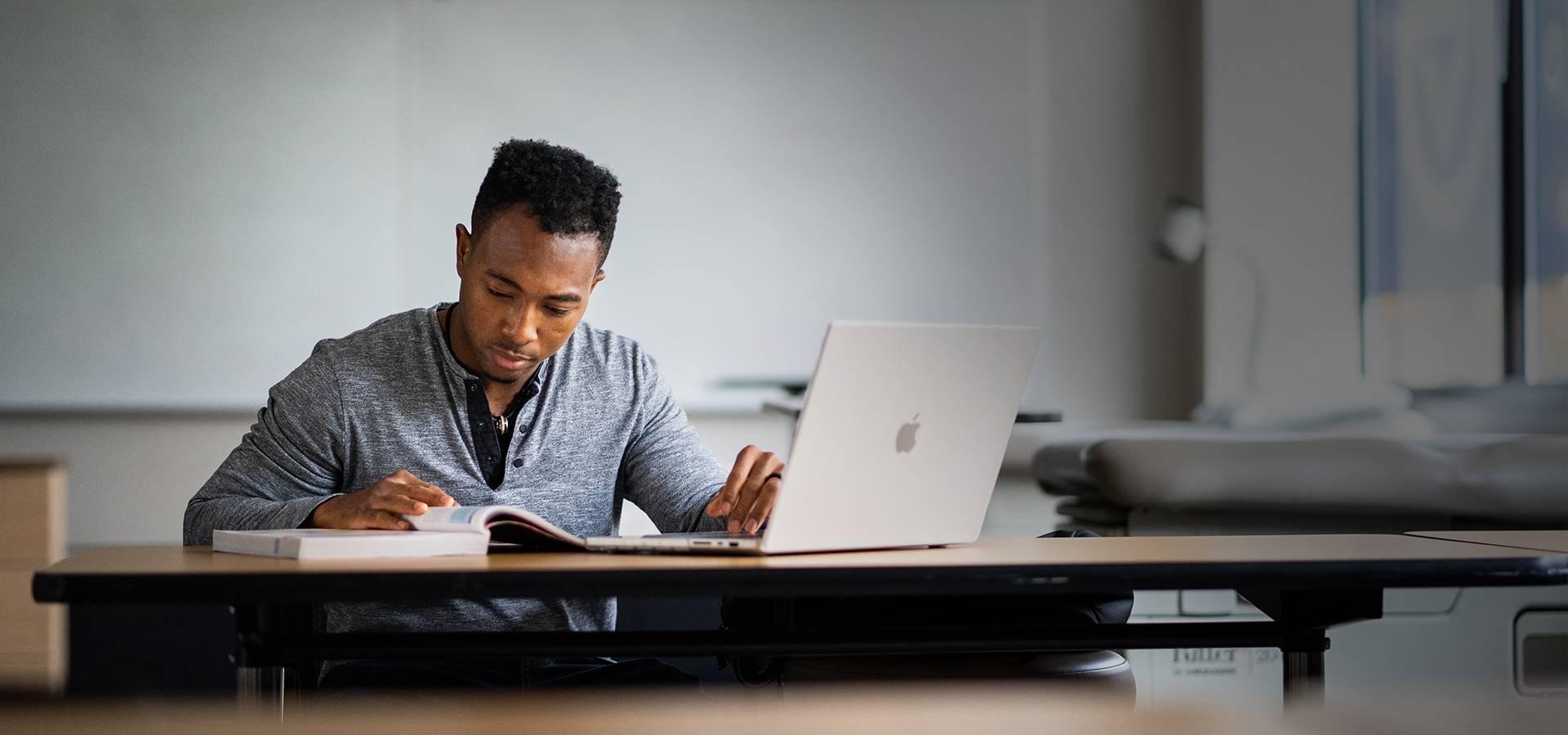 Student at desk with computer and textbook